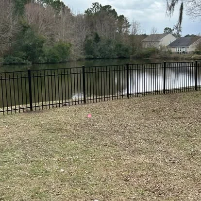 Open metal fence along a pond-side yard