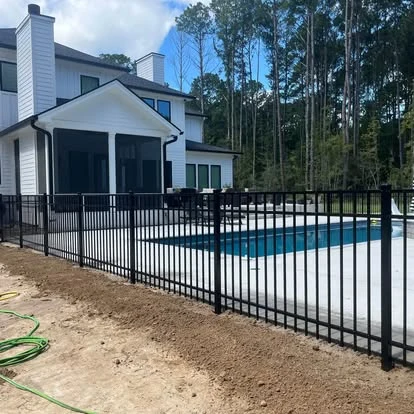 Black metal fence surrounding a backyard pool beside a screened porch